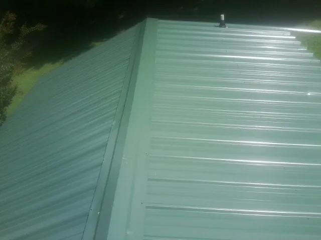 New green metal panels meeting at the ridge of a roof — Flat Roof Repair work by our crew in Cook Springs