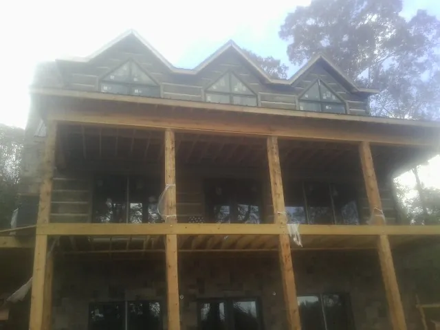 Dormers and porch framing on a large log home under construction — Roof Coating work by our crew in Cook Springs