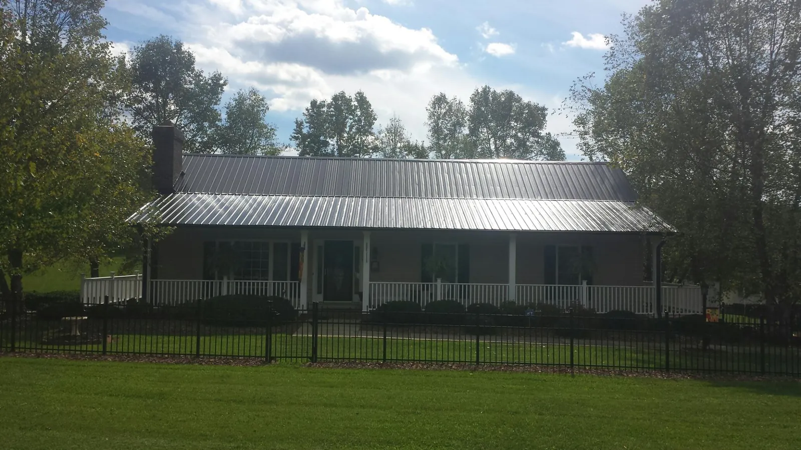 Gray metal roof on a brick ranch with a full width front porch — Gutter Guard Installation work by our crew in Cook Springs