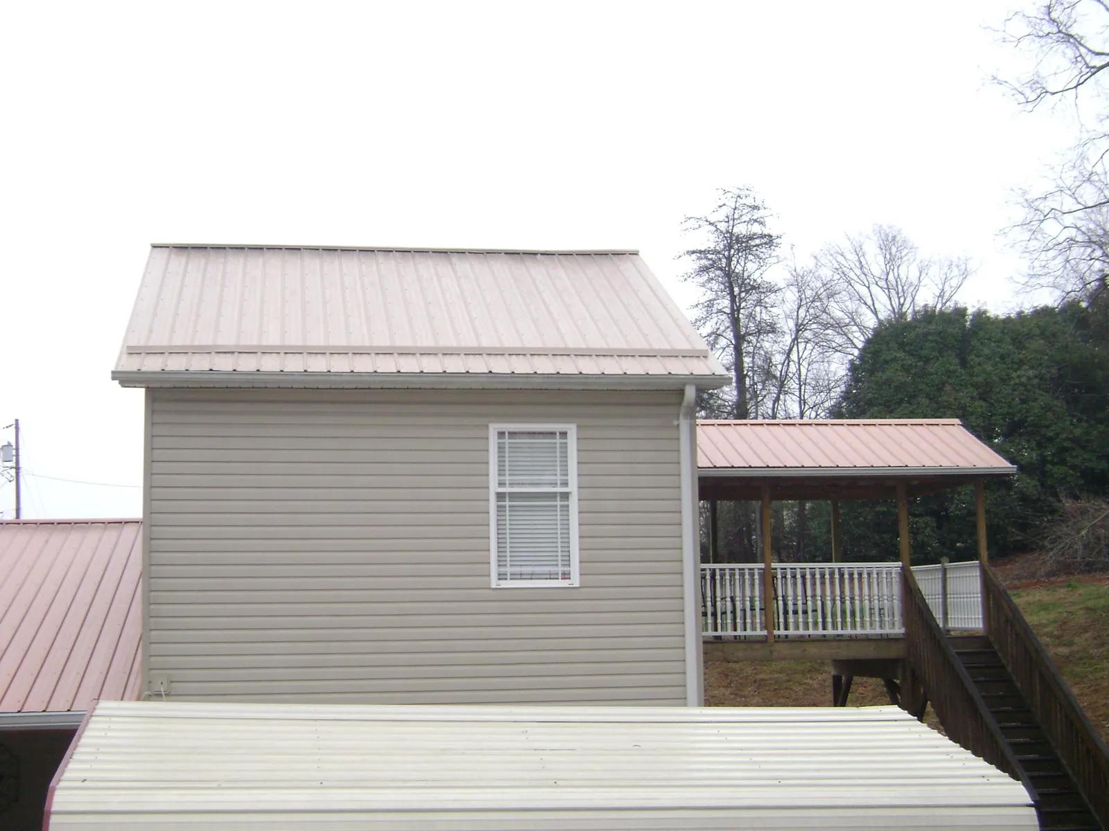 Tan metal roofs on a two story addition and attached porch, from a Roof Replacement job in Cook Springs