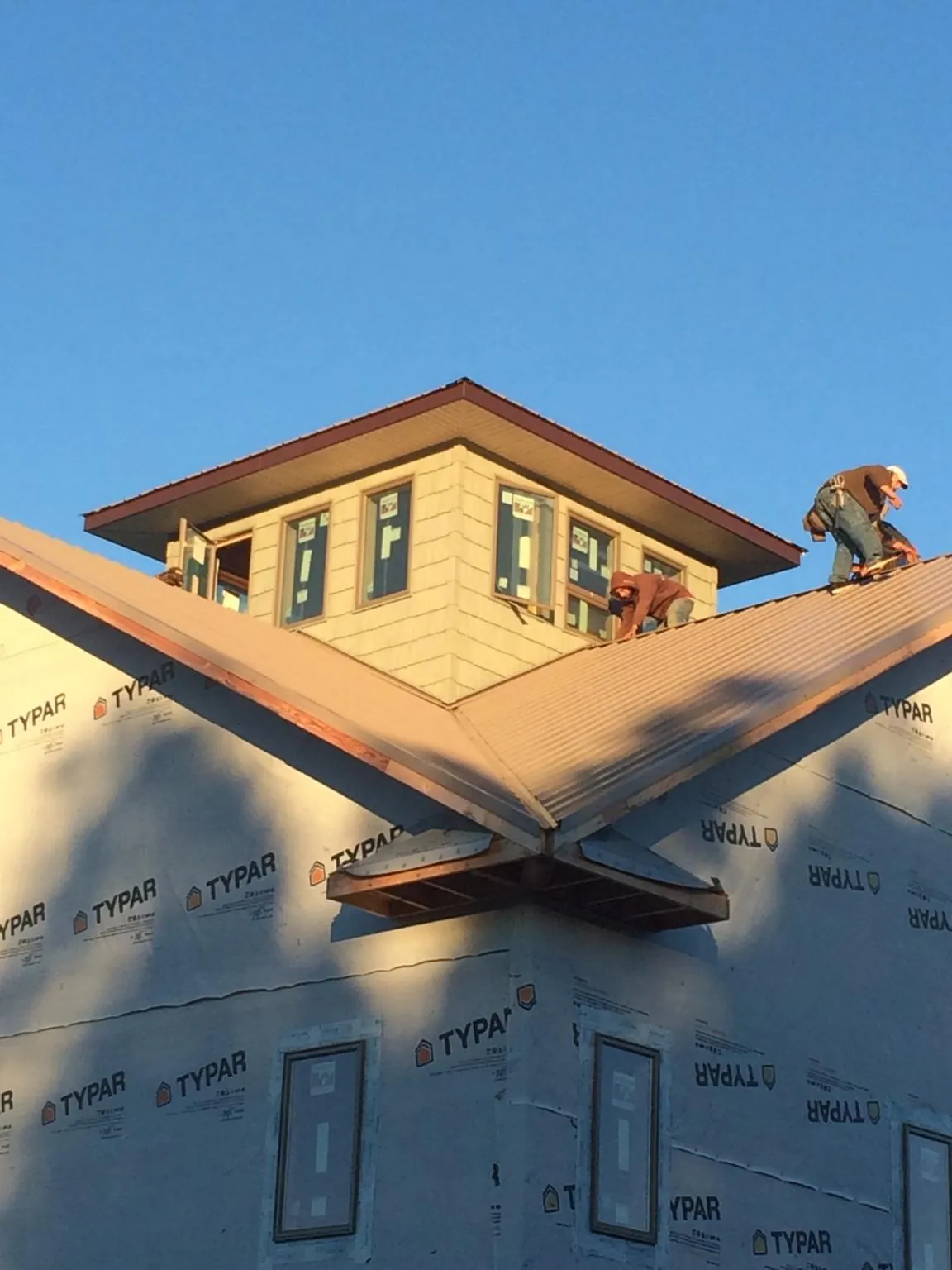 Roofers working around a rooftop cupola on a new metal roof at sunset — Roof Waterproofing in Cook Springs by Roofing Brothers